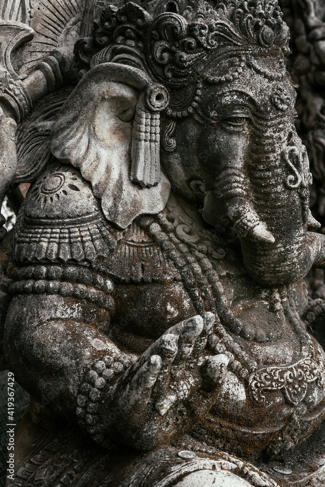 Close-up of an ancient sculpture in Indonesia on the island of Bali. Grey stone sculpture in the old town. Ganesh. Buddhist-related stone statues