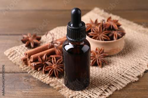 Anise essential oil and spices on wooden table