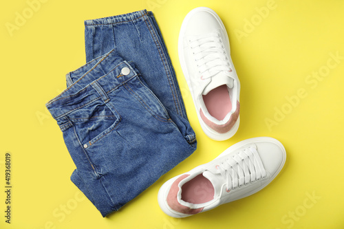 Wallpaper Mural Stylish white sneakers and jeans on yellow background, flat lay Torontodigital.ca