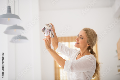 Blonde smiling housewife wiping a glass with a napkin