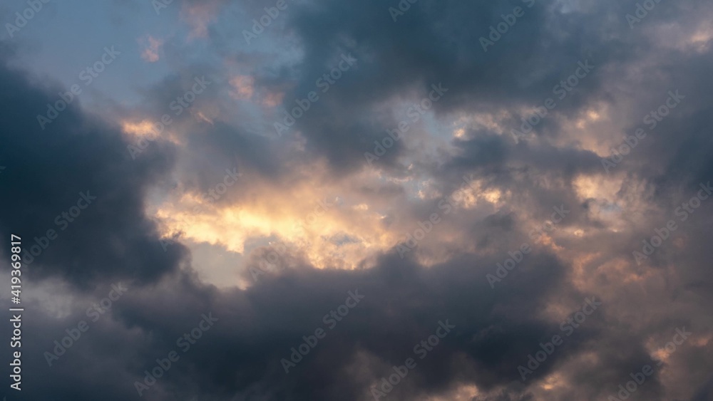 CLOUDS SHOWS THE IMPACT OF GLOBAL CLIMATE WARMING. Abstract clouds backgrounds. Dark dramatic clouds move fast. Ragged thunderclouds cover the sunny areas of the sunset sky