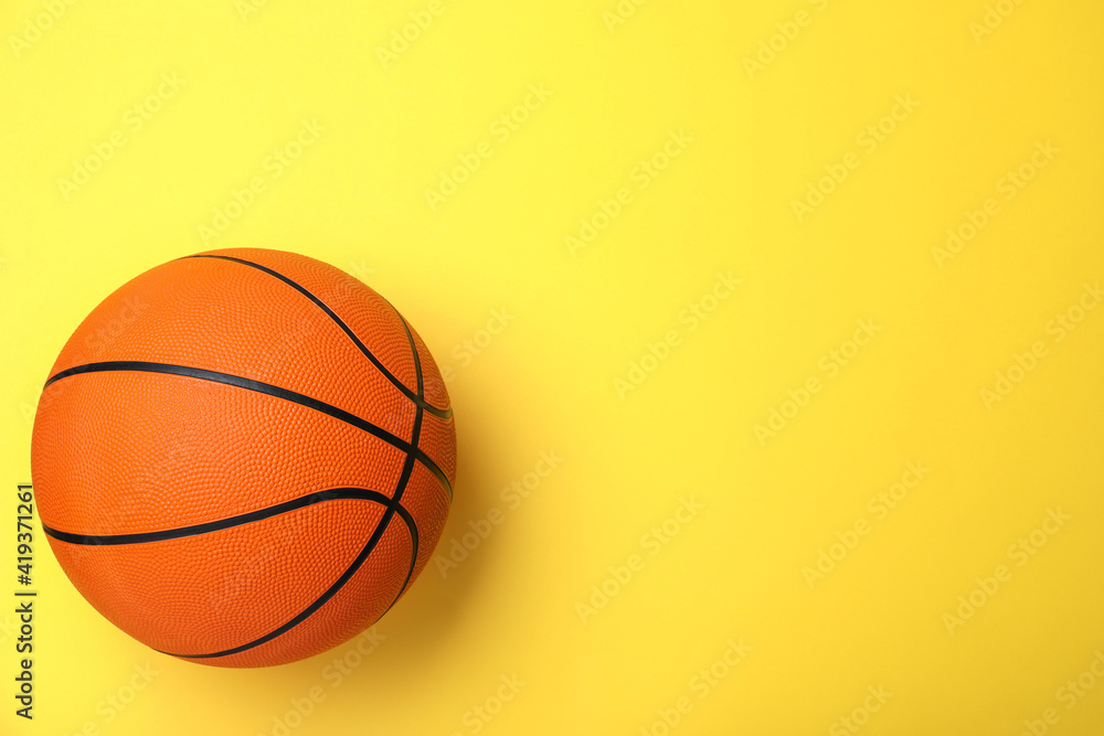Orange ball on yellow background, top view with space for text. Basketball equipment Orange ball on yellow background, top view with space for text. Basketball equipment