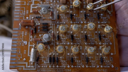 Radio Technician demonstrates Precious Radio Transistors, on an Electronic Board photo