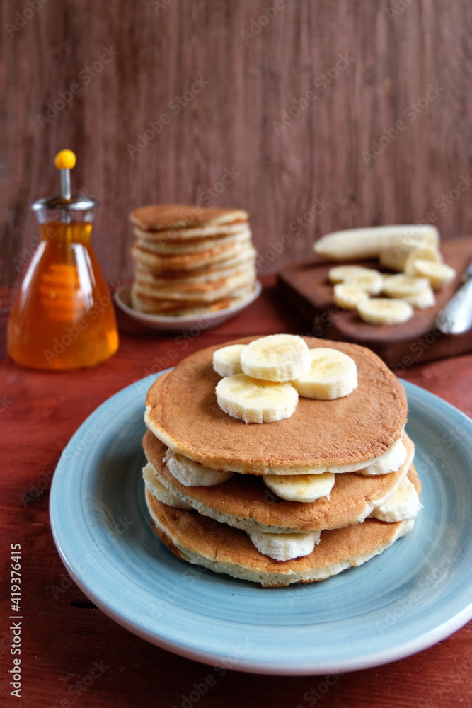 A stack of banana pancakes on a blue plate. Traditional American Breakfast. The concept of home made healthy food. Copy space. A stack of banana pancakes on a blue plate. Traditional American Breakfast. The concept of home made healthy food. Copy space.