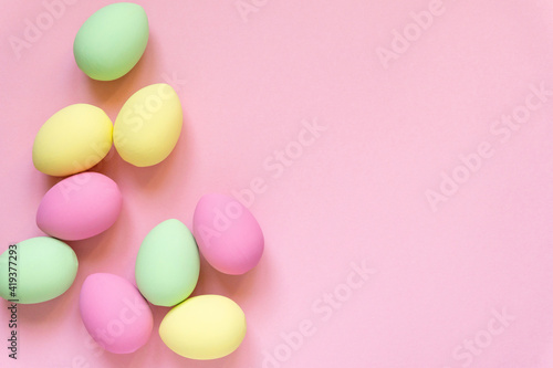 Easter flat lay. Eggs painted in pastel colors on pink background, space for text photo