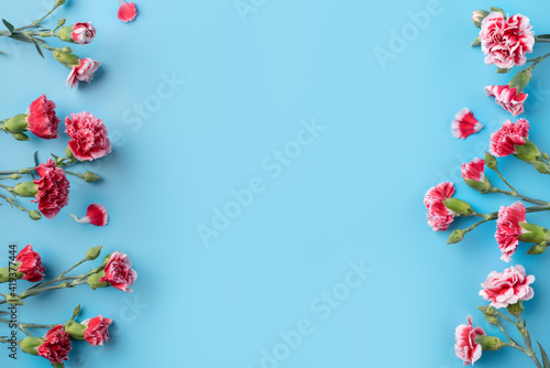 Concept of Mother's day holiday greeting gift with carnation bouquet on bright blue table background