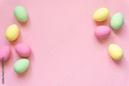 Easter flat lay. Eggs painted in pastel colors on pink background, space for text