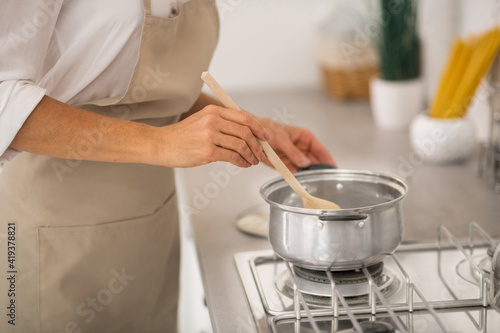 Close up picture of a woman stirring someting in a sausepan