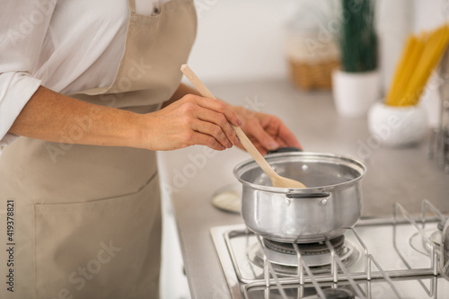 Close up picture of a woman stirring someting in a sausepan photo