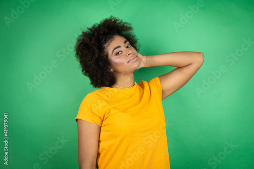 African american woman wearing orange casual shirt over green background with a happy face standing and smiling with a confident smile showing teeth
