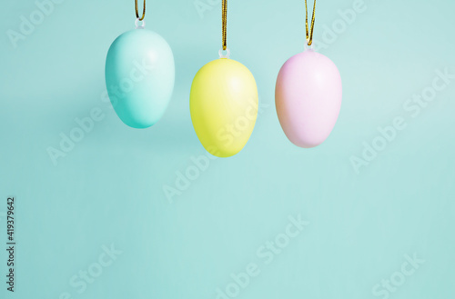 Easter background. A collection of Easter eggs in pastel colors hanging on a blue-green background. Easter concept