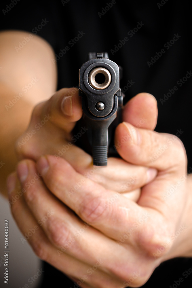 The criminal robber or gangster thief concept. Man holding gun aiming pistol in hand ready to shoot The criminal robber or gangster thief concept. Man holding gun aiming pistol in hand ready to shoot