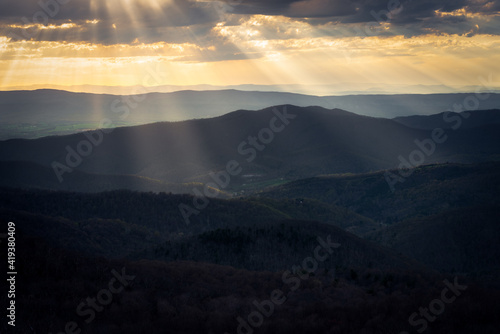 Golden crepuscular rays filling the valleys of Shenandoah National Park with sunset light.