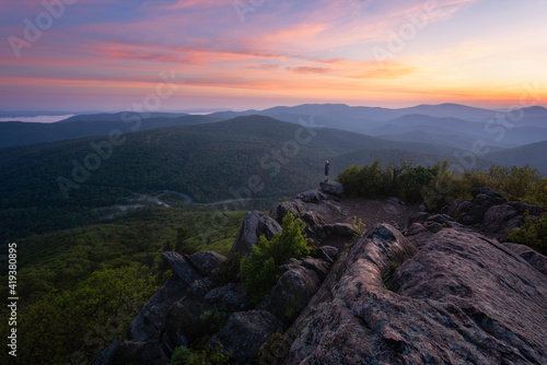 A hiker at the summit of Mary's Rock taking in a gorgeous Summer sunrise in Shenandoah National Park.