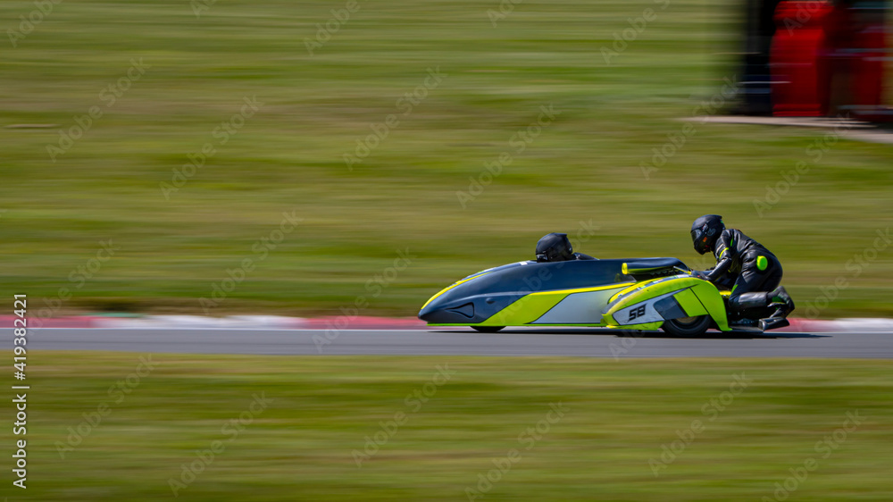 A panning shot of a racing sidecar as it corners on a track.
