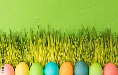 Spring Easter concept. Multicolored chicken-colored eggs lie on the luscious young grass.