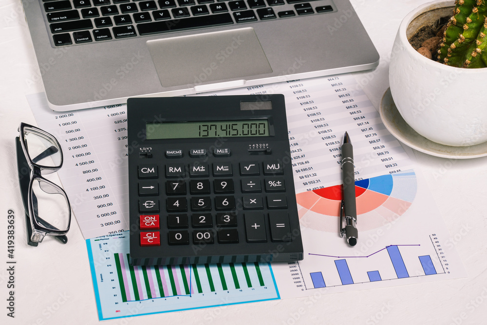 Calculator, laptop and financial documents on the desktop. Research and analytics in business. Enterprise development and banking. Accounting in the company Calculator, laptop and financial documents on the desktop. Research and analytics in business. Enterprise development and banking. Accounting in the company