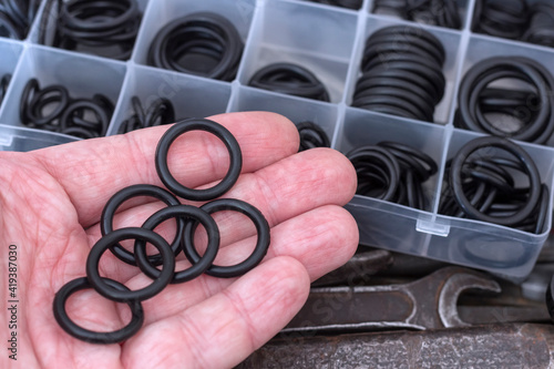 Rubber O-rings lying on the palm of your hand. A set of rubber gaskets for pneumatics and hydraulics.