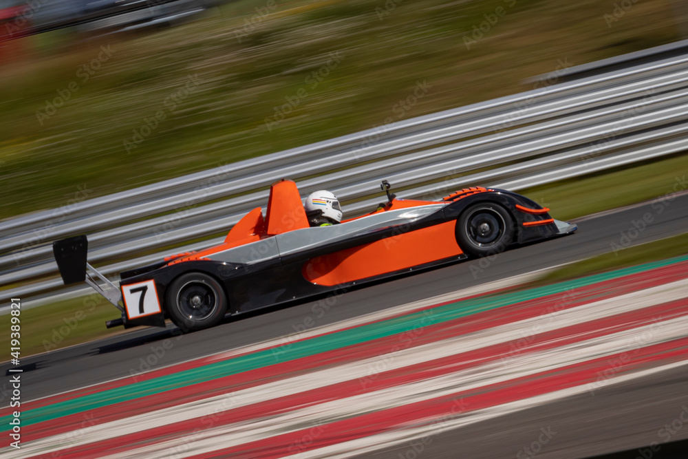 Obraz premium A panning shot of a racing car as it circuits a track.