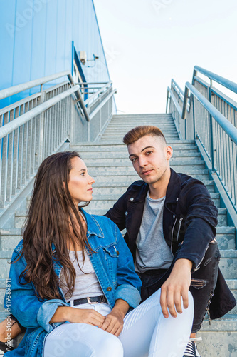 Lifestyle portrait of a beautiful young couple in love on the stairs of a building with blue background