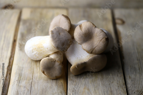 Raw eringi mushrooms on a wooden surface.