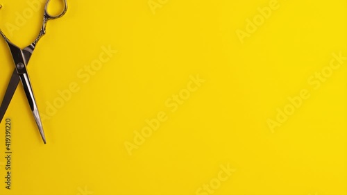 Stop motion animation template flat lay of professional hair cutting shears that cut in a circle on yellow background Hairdresser salon equipment concept with copy space Selfcare on lockdown time