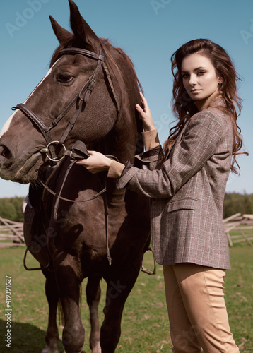 Beautiful brunette woman in an elegant checkered jacket with a horse