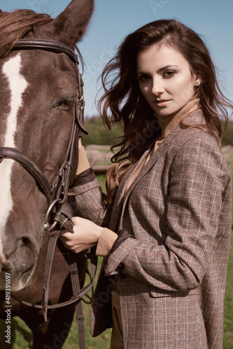 Beautiful brunette woman in an elegant checkered jacket with a horse