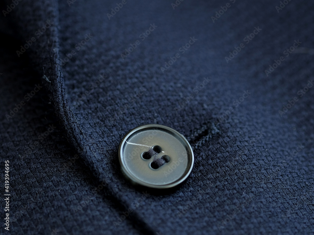 Button and sewing loop close-up on the textile surface. Design elements of a men's suit. Sewing, making clothes in a sewing workshop. Button and sewing loop close-up on the textile surface. Design elements of a men's suit. Sewing, making clothes in a sewing workshop.
