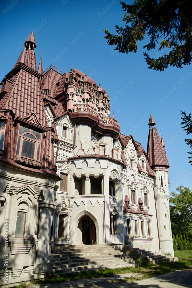 Scenic view over whimsical castle with red roof, surrounded by green trees. Beautiful historical landscape. Summer getaway vacation. Architectural sightseeing tour