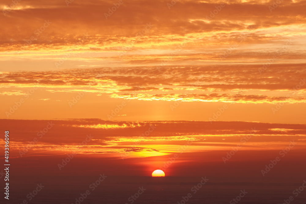 late beautiful sunset with clouds, sun goes down behind dark horizon, natural beauty background