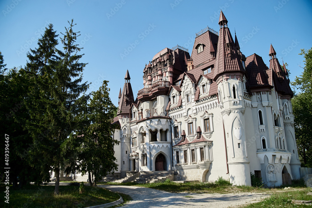 Scenic view over whimsical castle with red roof, surrounded by green trees. Beautiful historical landscape. Summer getaway vacation. Architectural sightseeing tour