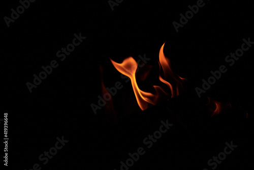 Bright vivid orange and yellow tongues of flame on black background. Burning bonfire at night. Sport tourism in summer.
