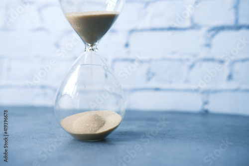 hourglass on table, sand flowing through the bulb of sandglass
