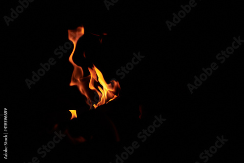 Bright vivid orange and yellow tongues of flame on black background. Burning bonfire at night. Sport tourism in summer. © Natalia
