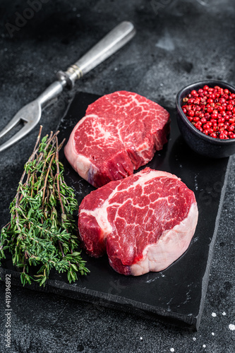 Prime Raw Fillet Mignon tenderloin steaks with thyme. Black background. Top view