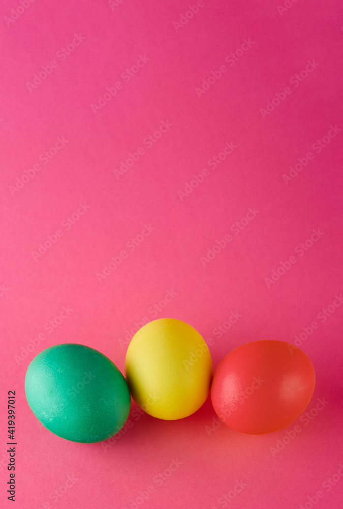 Vertical banner with green, yellow and red eggs on pink background. Happy Easter.