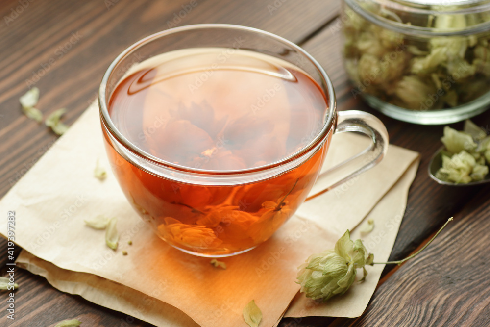 Hop herbal tea with dry herb on wooden table, natural decoction is used against insomnia, depression and for menopause and skin, hair care, closeup, copy space, natural medicine, naturopathy concept Hop herbal tea with dry herb on wooden table, natural decoction is used against insomnia, depression and for menopause and skin, hair care, closeup, copy space, natural medicine, naturopathy concept