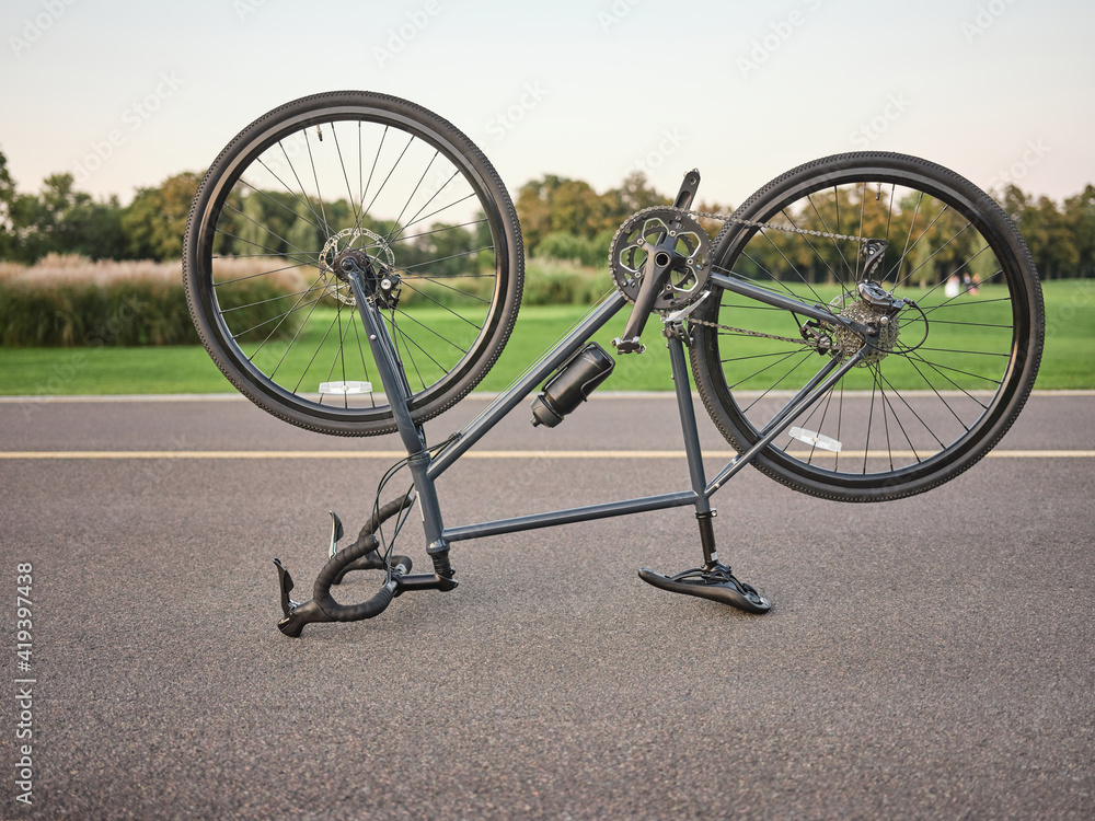 Fototapeta premium Broken bike. Malfunctioning upside down road bicycle parked for repairing in public park on a daytime