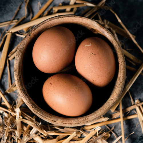 Fotografi brown chicken eggs in a boxwood bowl
