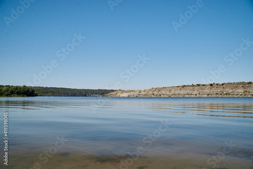 Scenic view over wide river and it s bank. Beautiful natural countryside landscape with blue sunny sky. Summer getaway vacation into isolated places. Calm water - perfect for meditation.