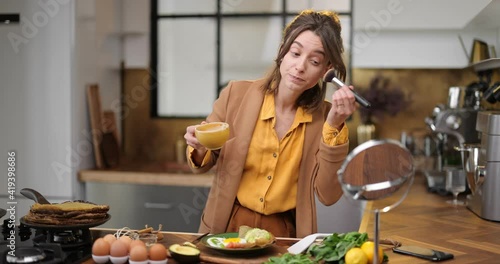 Fussy young businesswoman in a hurry to work in the morning, drinking coffee, chatting on phone and apllying makeup on the go photo