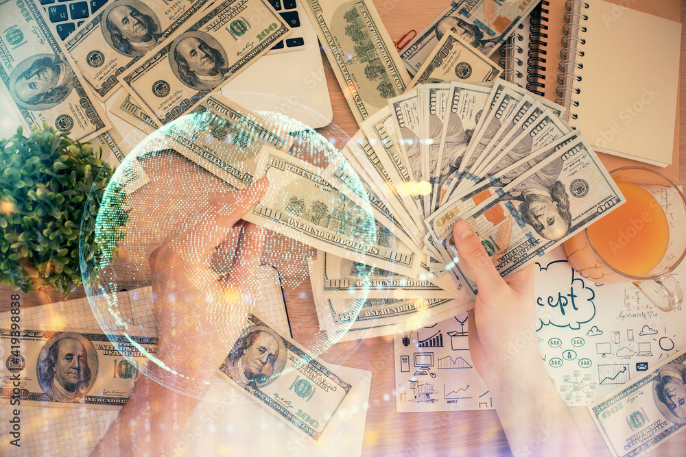 Double exposure of world map drawing hologram and us dollars bills and man hands. Double exposure of world map drawing hologram and us dollars bills and man hands.