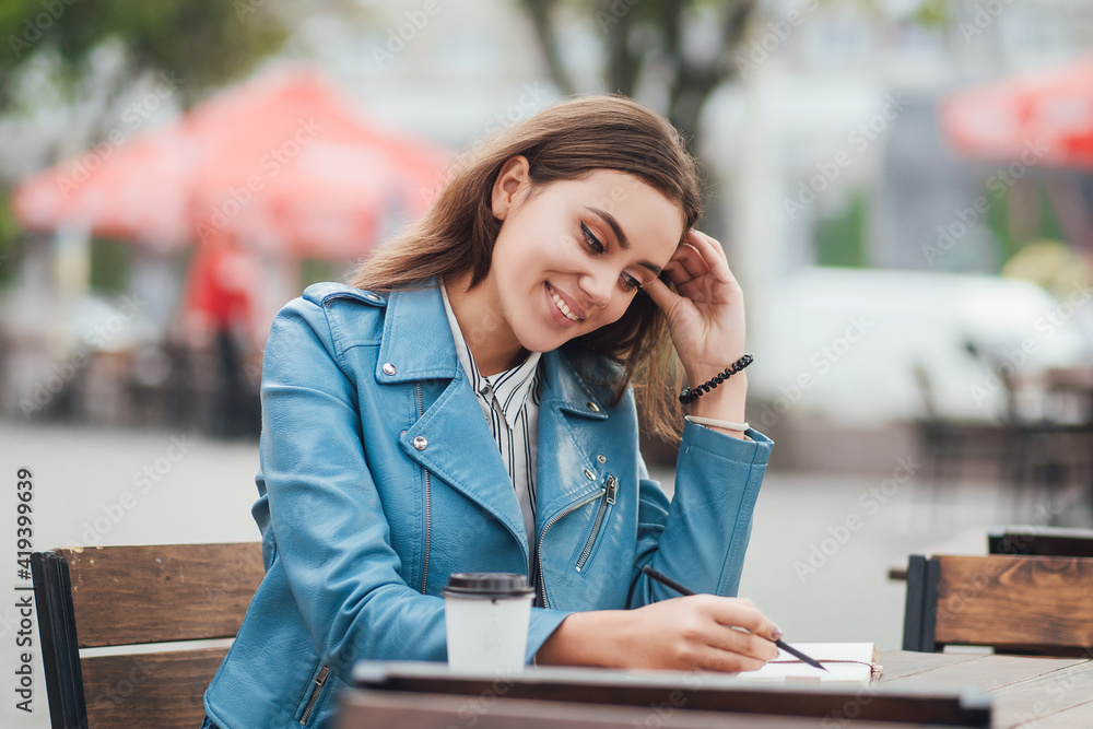 Attractive young woman working outdoors at a table in a cafe, happy woman smiling, freelancer work, lifestyle, urban lifestyle, worker Attractive young woman working outdoors at a table in a cafe, happy woman smiling, freelancer work, lifestyle, urban lifestyle, worker