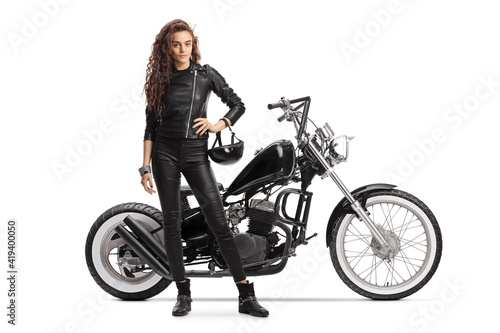 Female biker holding a helmet and posing with a chopper motorbike