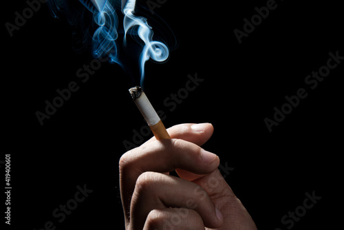 A Cropped of man hand holding cigarette black background