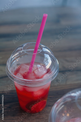 Cold beverage, iced tea, Hibiscus and lime mocktail with ice cubes in glass with cap and straw on cafe table background. Soft focused close up shot photo