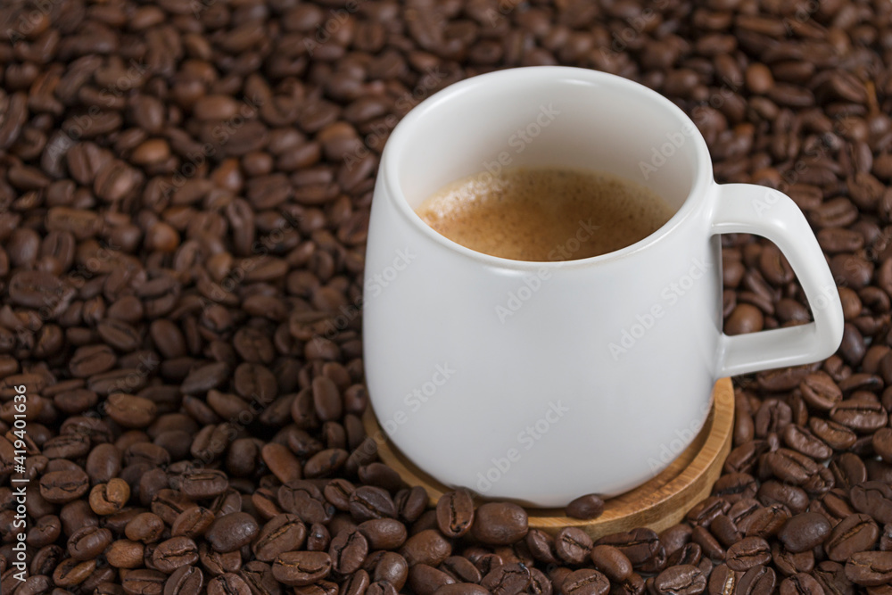 white cup of coffee on the background of coffee beans. close up white cup of coffee on the background of coffee beans. close up
