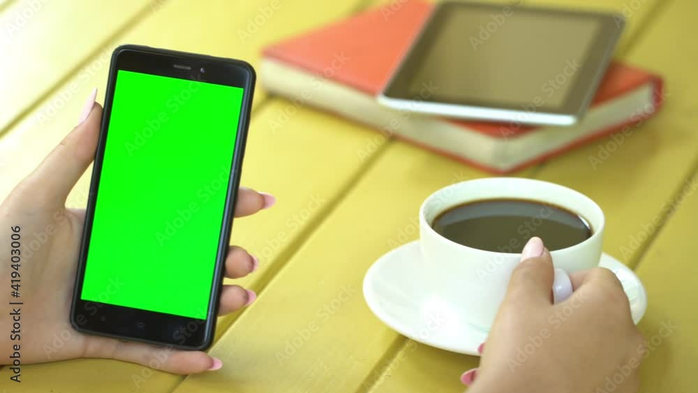 business woman using smartphone viewing green screen on mobile phone browsing chroma key online watching enjoying drinking coffee reading social media close up hands business woman using smartphone viewing green screen on mobile phone browsing chroma key online watching enjoying drinking coffee reading social media close up hands