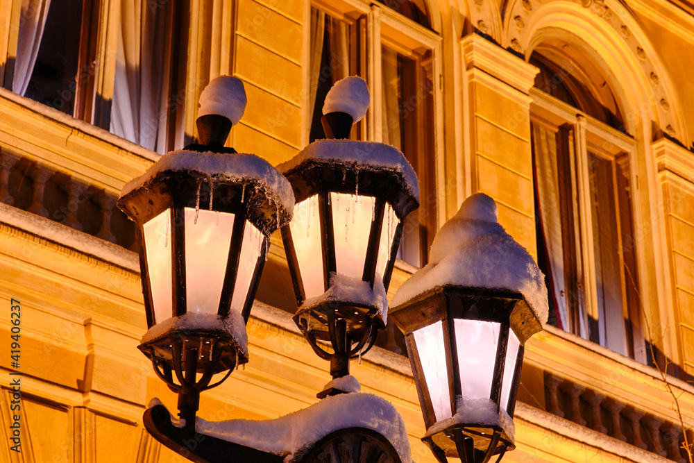The classic old street lamps during the snowfall in European city.